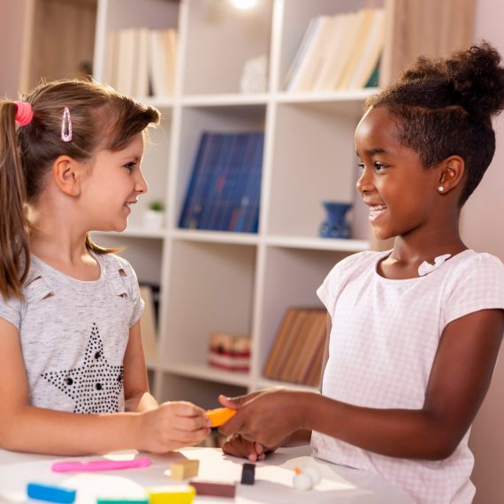 Two preschoolers playing with colorful plasticine and having fun